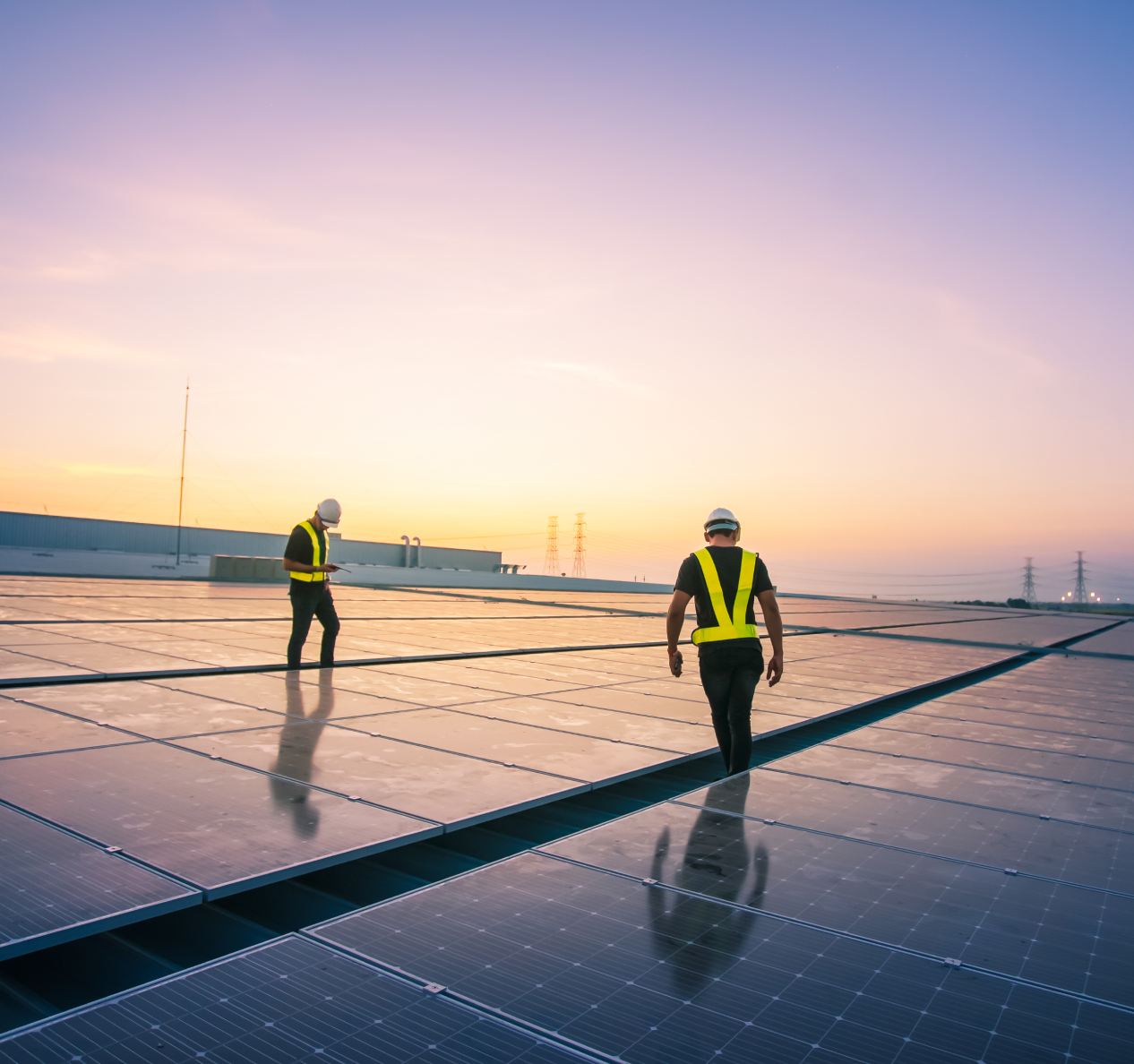 Solar technicians walking on rooftop solar array at sunset